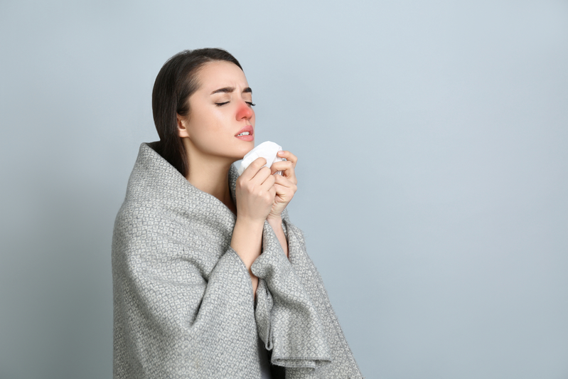 woman with red nose holding tissue to blow her congested nose
