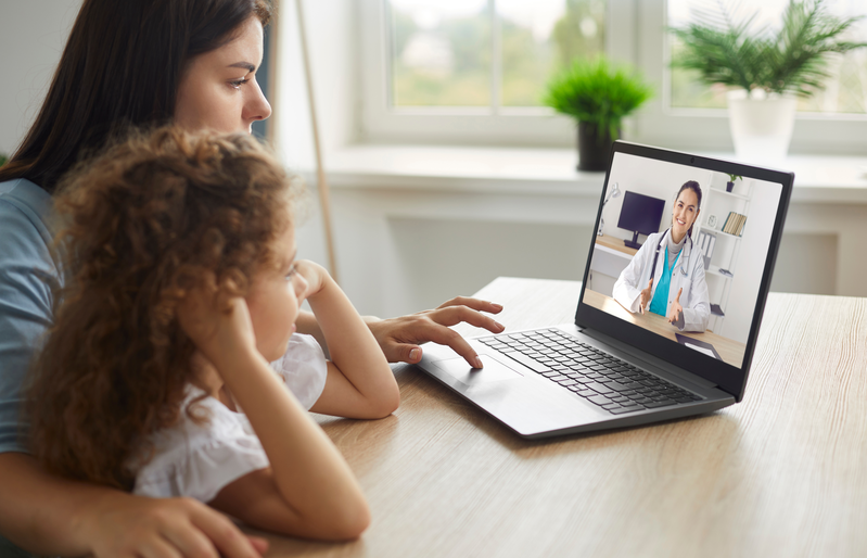 mother and daughter looking at computer during telehealth appointment