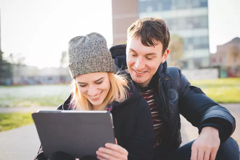 young couple outside looking at notebook