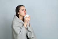 woman with red nose holding tissue to blow her congested nose