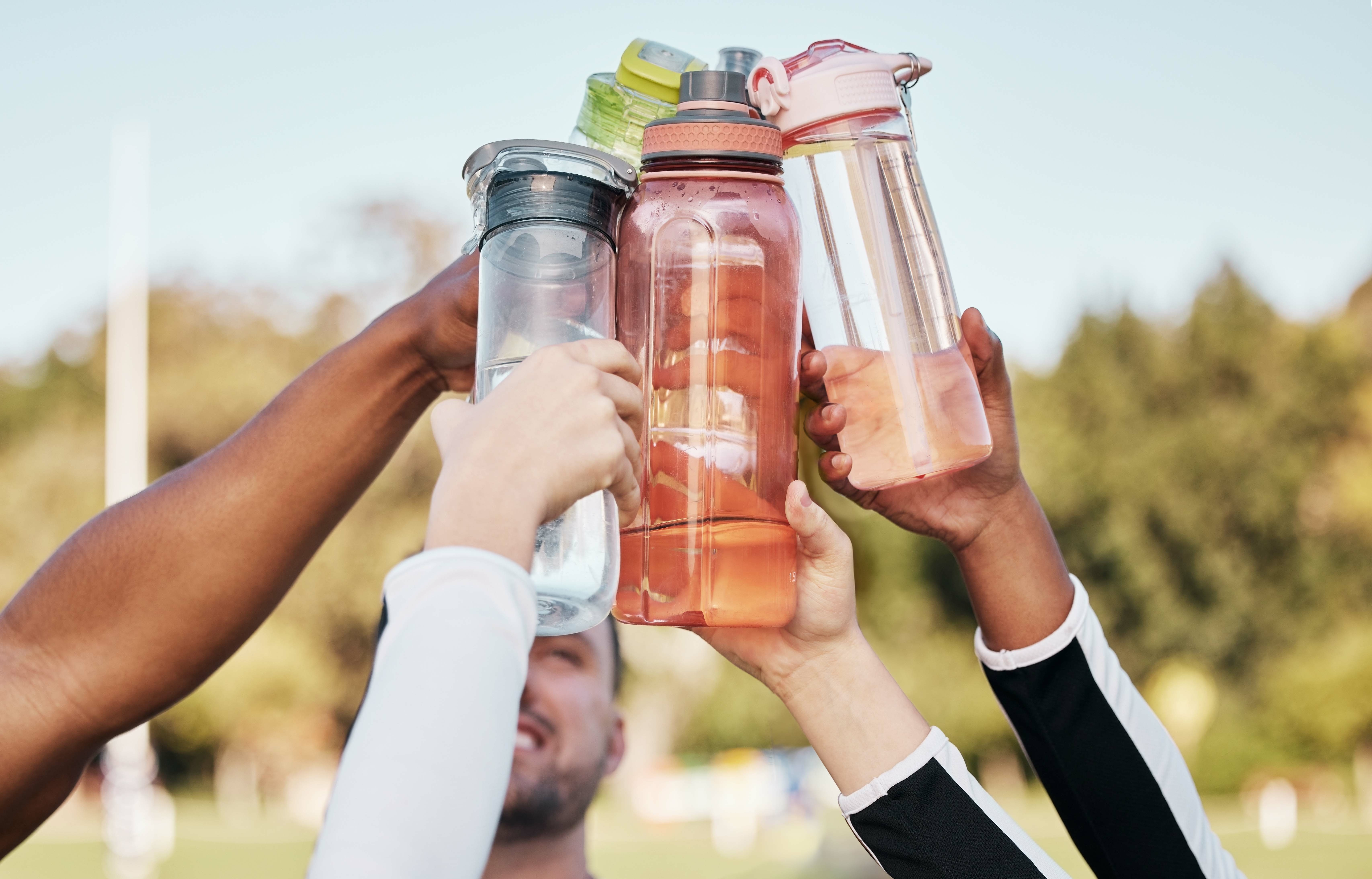 group of friends holding up water bottles to one another