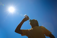 senior man drinking from bottle of water under sunny, cloudless sky